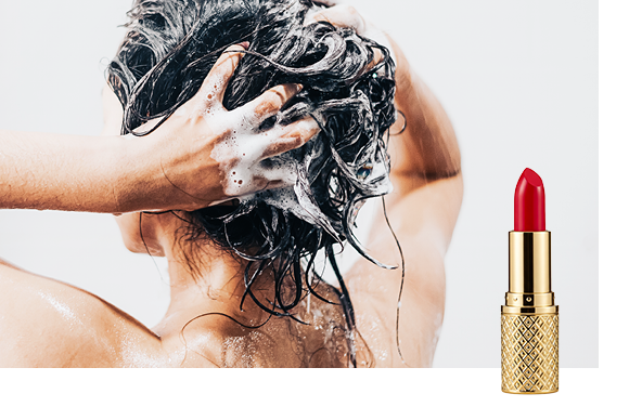 A woman washing her hair in the background and a stick of lipstick in the foreground
